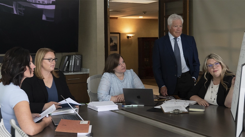 Legal team gathered around a conference table reviewing case documents in a boardroom.