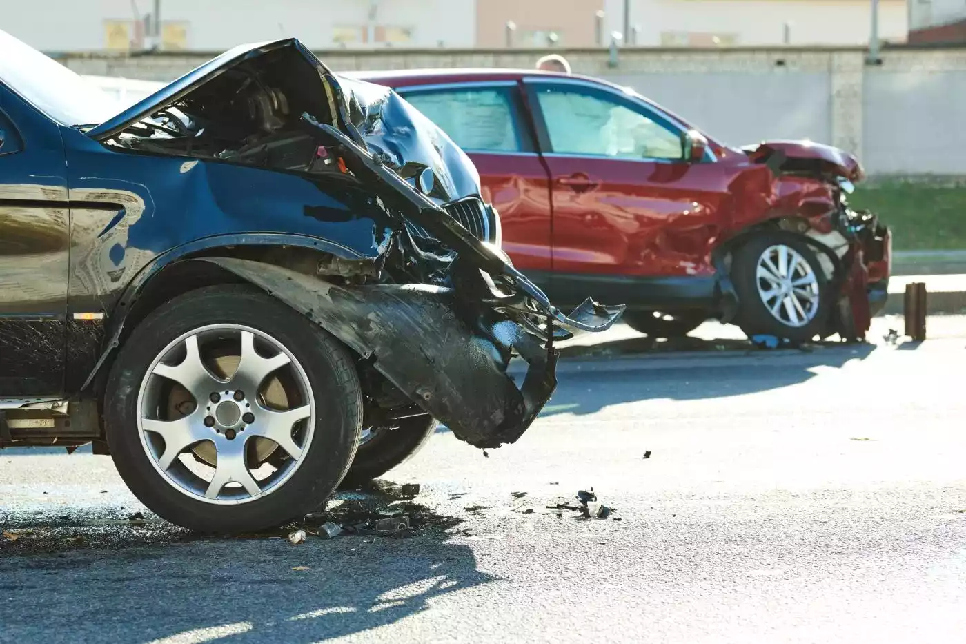 A dark blue SUV and a red car with heavily crumpled front ends after a head-on collision.