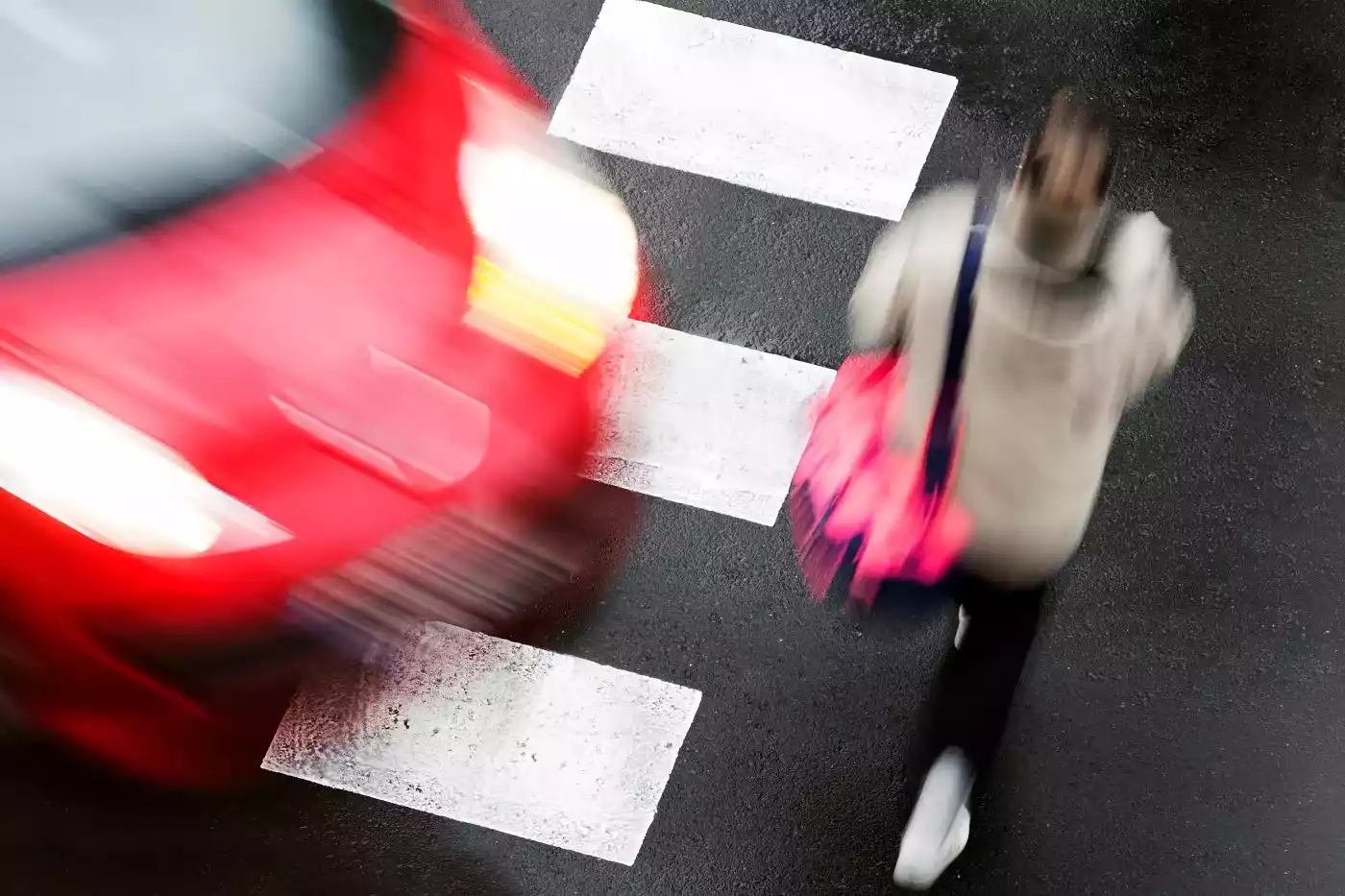 A high-speed scene of a red vehicle approaching a marked crosswalk.