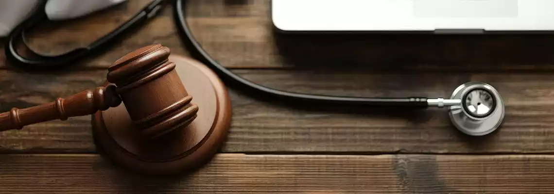 Medical gavel and stethoscope on a wooden table.
