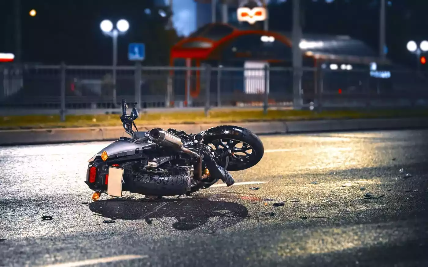 A motorcycle lies crashed on its side on a wet city street at night.