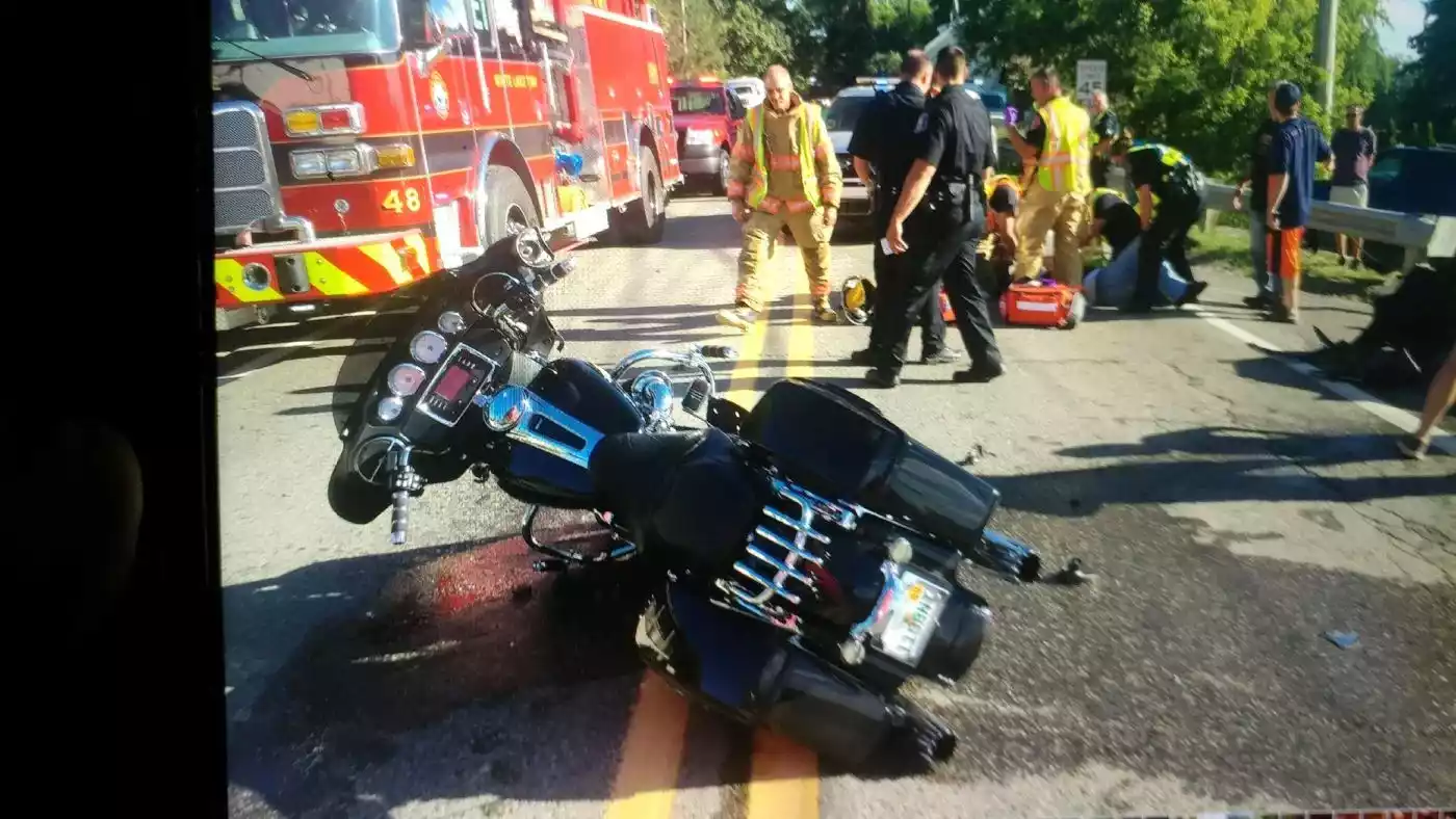 Emergency responders tend to a motorcycle accident scene on a road near a fire truck.