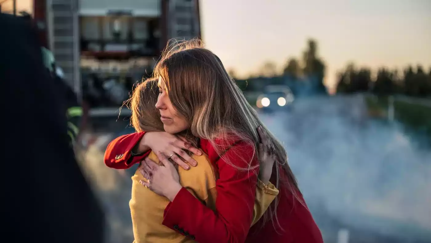 A emotional scene of a person comforting another following a vehicular incident.