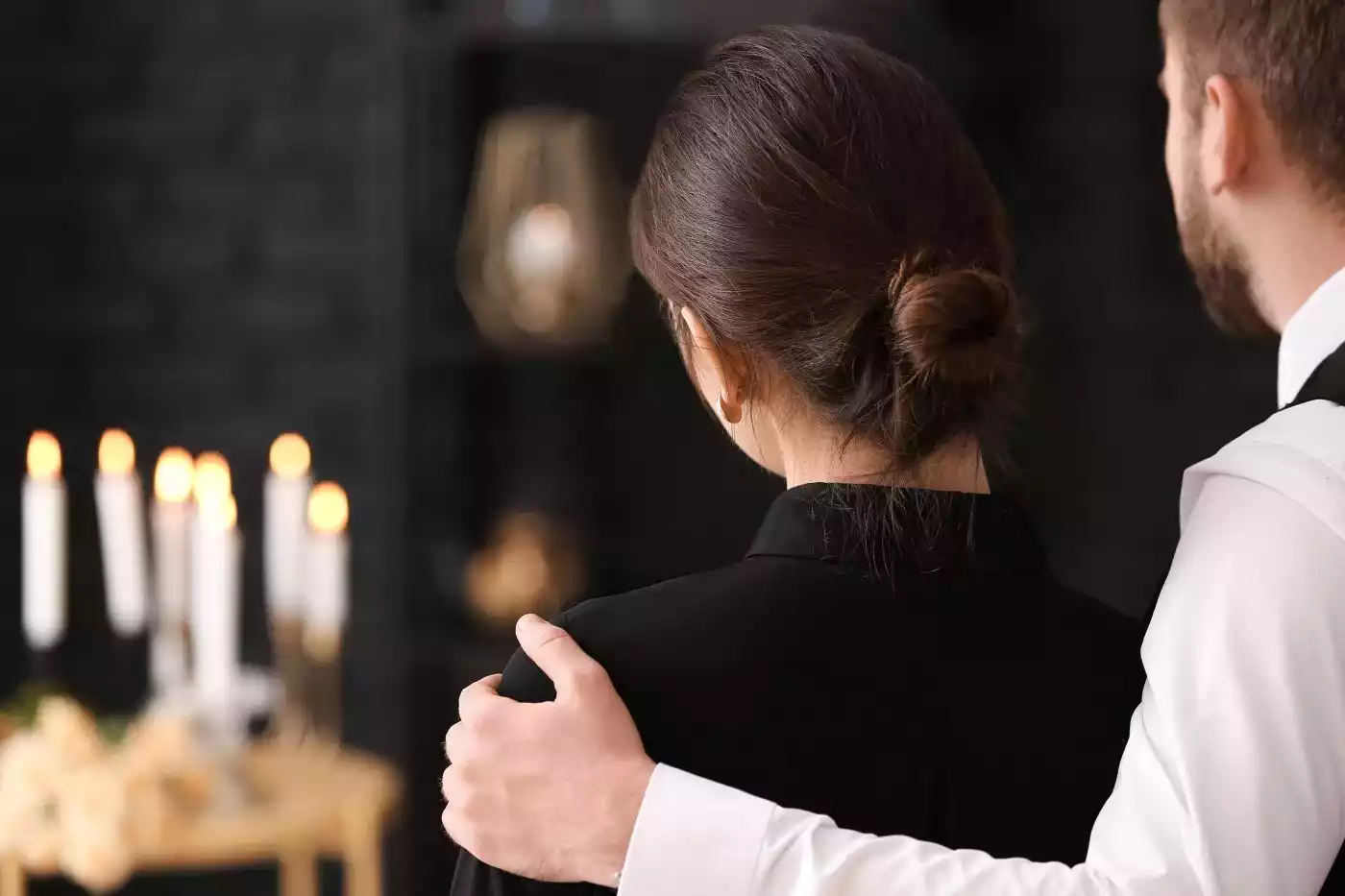 A quiet moment of support between two individuals dressed in formal black and white attire.