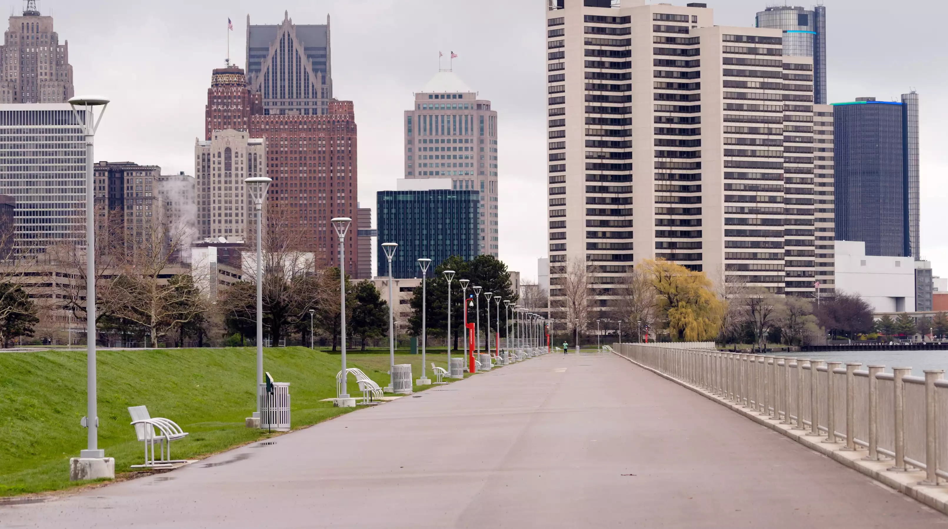 Detroit International Riverwalk path facing the city skyline and skyscrapers on a cloudy day.